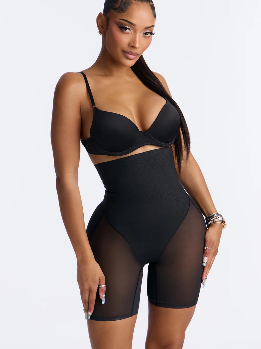 Woman wearing a black bodysuit with sheer panels on a white background
